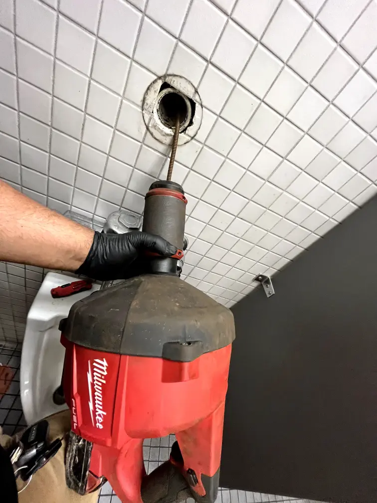 Commercial plumber working on pipes in an office building